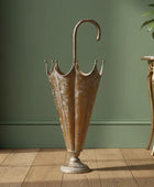 Bronze umbrella stand on a wooden floor against a green wall