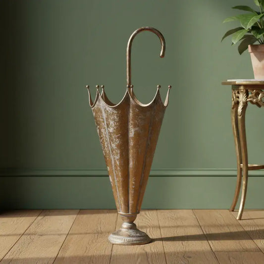 Bronze umbrella stand on a wooden floor against a green wall