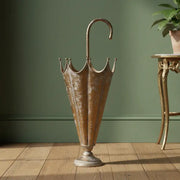 Bronze umbrella stand on a wooden floor against a green wall