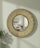 Round decorative mirror with circular patterns on a wall, reflecting a room with furniture.