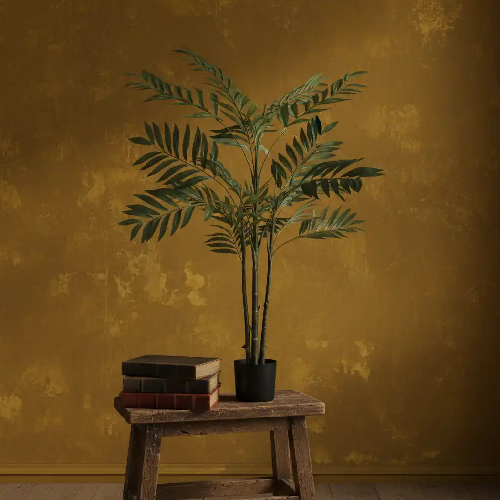 Potted plant on a wooden stool against a textured mustard yellow wall