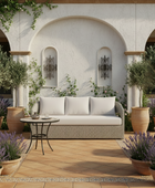 Outdoor patio with a gray sofa, chairs, and potted plants on a sunny day.