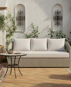 Outdoor patio setting with a wicker sofa, small table, and decorative elements.