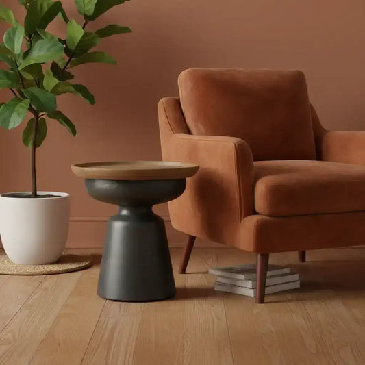 Brown armchair with a wooden side table and plant in a room with a brown wall.