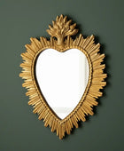 Decorative gold heart-shaped mirror on a dark green background