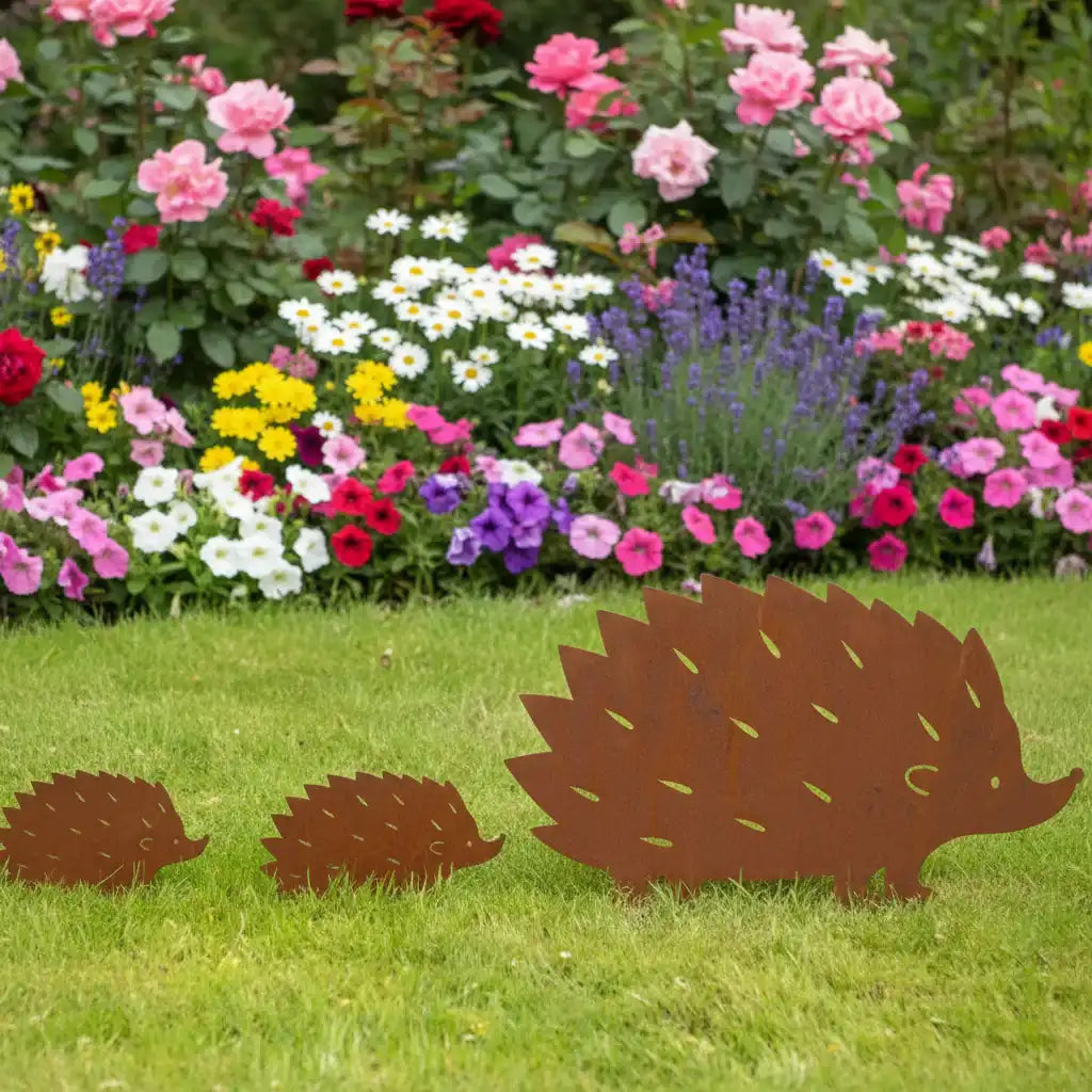 Three brown hedgehog-shaped garden decorations in front of a colorful flower bed.