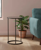 Teal armchair and black metal side table in a room with pink walls and a plant.
