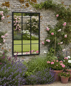 Garden scene with a brick wall, mirror, and potted plants