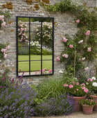 Garden scene with a stone wall, mirror, and potted plants