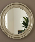 Round mirror with a beige frame on a brown wall