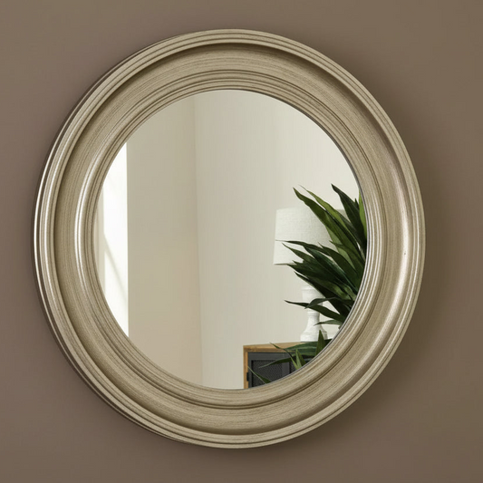 Round mirror with a beige frame on a brown wall