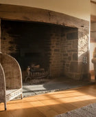 Living room with stone fireplace, wicker chair, and armchair.