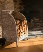 Wicker log holder with stacked firewood in front of a stone fireplace.