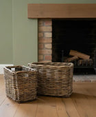 Two wicker baskets in front of a brick fireplace with wooden mantel.