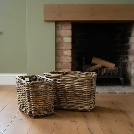 Two wicker baskets in front of a brick fireplace with wooden mantel.