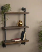 Wooden shelf with metal pipes against a beige wall, decorated with books and a gold vase.