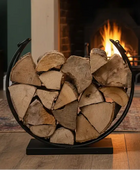Firewood arranged in a circular metal holder in front of a burning fireplace.