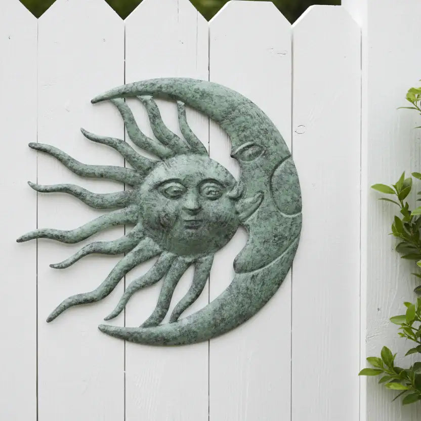 Decorative wall art of a sun and moon with faces on a white wooden background