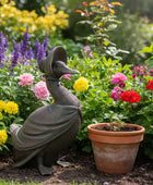Garden statue of a bird with a hat among colorful flowers and plants