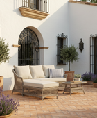 Outdoor patio with wicker furniture, cushions, and potted plants in a Mediterranean-style setting.