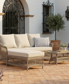 Outdoor patio set with wicker furniture and cushions on a tiled patio.