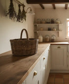 Kitchen with wooden countertop, wicker basket, and shelves with jars.