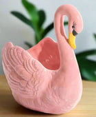 Pink swan-shaped ceramic planter on a white background
