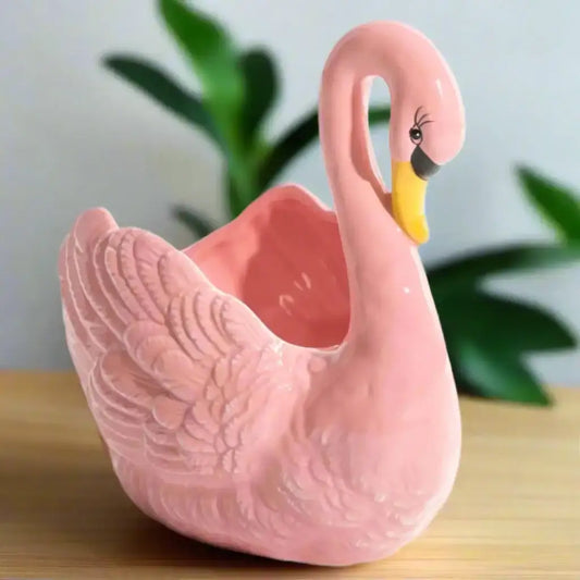 Pink swan-shaped ceramic planter on a white background