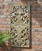 Decorative wall panel with intricate carvings on a brick wall