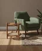 Green armchair with a wooden side table in a room with a brown wall and wooden floor.