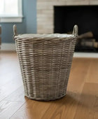 Wicker laundry basket on a wooden floor with a blurred background of a living room.