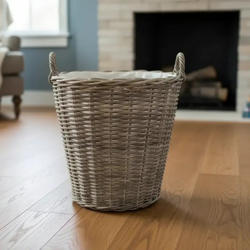 Wicker laundry basket on a wooden floor with a fireplace in the background