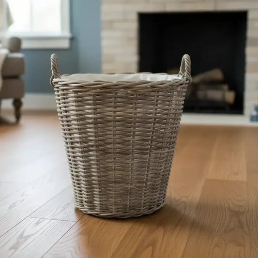Wicker laundry basket on a wooden floor with a fireplace in the background