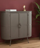 Gray cabinet with books and a lamp against a red wall with a plant on the right.