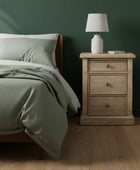 Bedroom with a wooden nightstand and lamp against a dark green wall.
