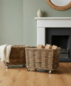 Two wicker baskets on wheels in a room with a fireplace and green walls.