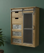 Wooden cabinet with glass door and drawers against a green wall with a plant on a small table.