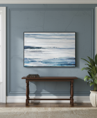 Abstract painting on a wall above a wooden console table with a plant in a room.