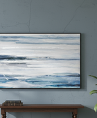 Abstract painting with blue and white stripes on a gray wall above a wooden console table.