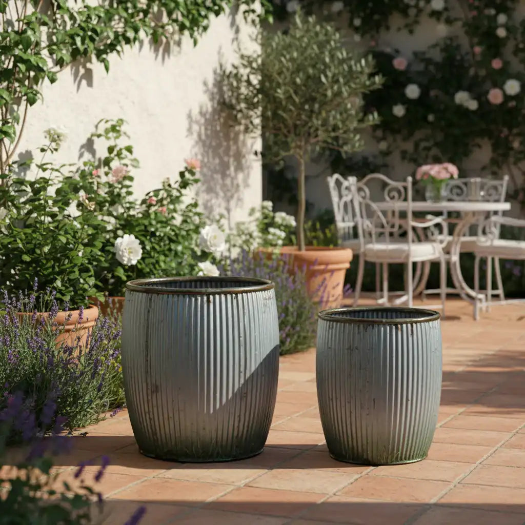 Two gray planters on a patio with garden and table in the background
