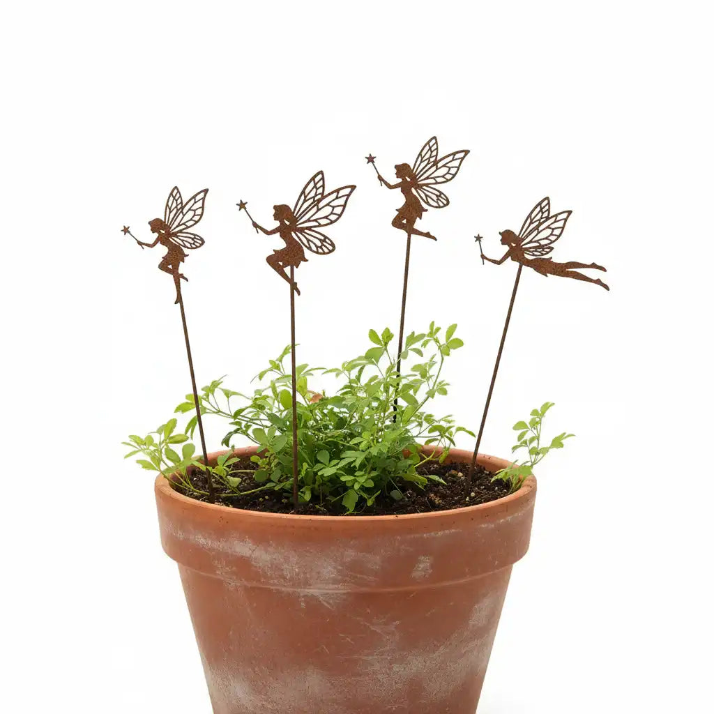 Terracotta pot with green plants and four decorative fairy stakes on a white background