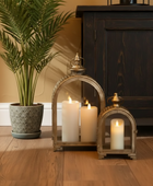 Decorative lanterns with candles on a wooden floor next to a plant and dark wooden cabinet.