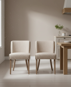 Two beige chairs in a modern kitchen setting with a wooden table and neutral walls.