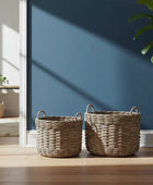 Two woven baskets and a potted plant on a wooden floor against a blue wall.