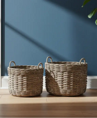 Two wicker baskets on a wooden floor against a blue wall.