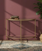 Gold console table against a pink wall with a plant and books on it