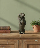 Decorative dog figurine on a wooden surface with books and a plant against a green wall.
