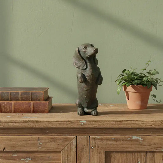 Decorative dog figurine on a wooden surface with books and a plant against a green wall.