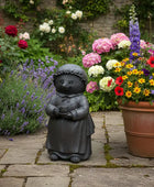 Decorative garden scene with a small statue, potted flowers, and lush greenery.