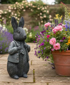Decorative rabbit statue in a garden setting with flowers and plants.